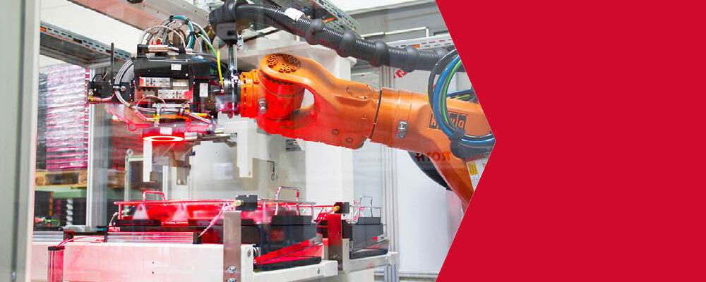 Ein orangener Industrieroboter der hinter einer Scheibe arbeitet